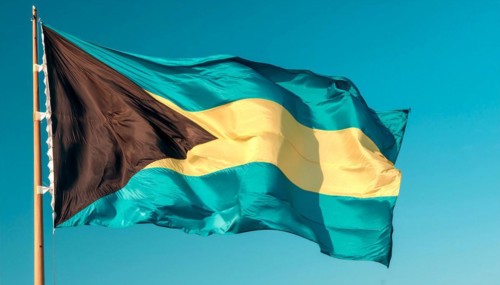 The flag of the Bahamas flutters in the wind, isolated against a blue sky