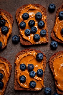 Rye bread with peanut paste and fresh blueberries, top view, no people