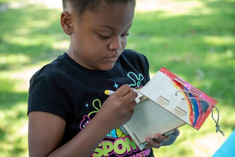 Detroit, Michigan, A girl paints a birdhouse she has put together at the annual 'Summer Sizzler'