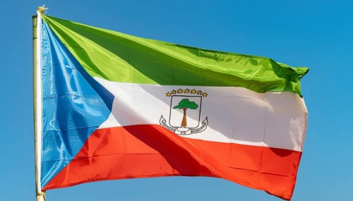 The flag of Equatorial Guinea flutters in the wind, isolated against a blue sky