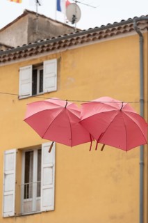In the perfume town of Grasse, two red umbrellas hang between the houses, Grasse,