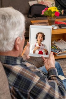 Symbolic image of telemedicine, elderly patient speaking to a doctor in a video conference from