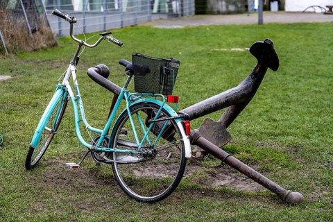 Bicycle, ladies' bicycle, well secured with a bicycle lock to an iron ship's anchor, in
