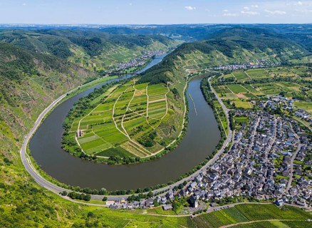 A river bend cuts through a hilly landscape with vineyards and a neighbouring village, surrounded
