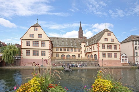 Musée historique, historical museum and river Ill with floral decoration, church tower of the