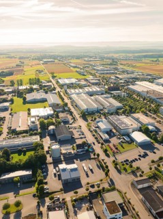 An industrial area with several factory buildings and neighbouring fields, seen from a bird's eye