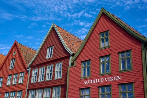 Traditional red wooden houses under a blue sky with pitched roofs and multiple windows in a sunny