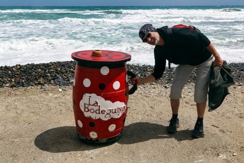 Red outdoor bar table, hiker, tourist holding jug, bar, beach bar, Cabo de Gata Natural Park,