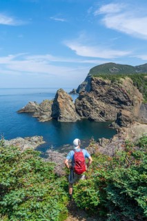 Hiker stands at a viewpoint above the rocky coast in Bottle Cove Provincial Park, Bay of Islands,