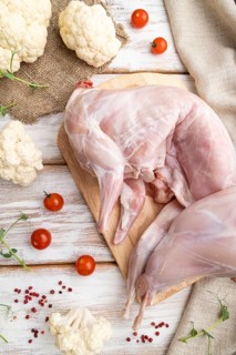 Whole raw rabbit with cauliflower, tomatoes and spices on a white wooden background and linen