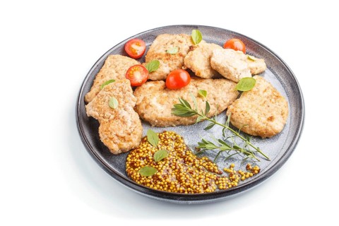 Fried pork chops with tomatoes and herbs on a gray ceramic plate isolated on white background. side