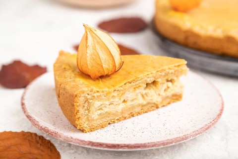 Autumn onion pie decorated with leaves and cup of coffee on gray concrete background. Side view,