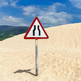 Moving dune with traffic sign, caution narrowed lane, narrowing of lane, dune, coastline near
