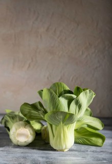 Fresh green bok choy or pac choi chinese cabbage on a gray wooden background. Hard light, contrast.
