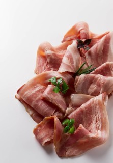 Raw bacon, sliced, with micro greenery and spices, on a white background, close-up