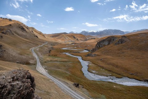 Road, track between hills with yellow grass, Kol Suu river winds through a mountain valley, Naryn