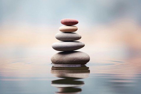 Stack of zen stones on water with a nature background. The image conveys a sense of balance,