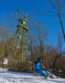 Winter in the Ruhr area, toboggan run on a forest path at Lake Baldeney, headframe of the former