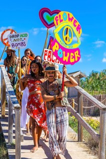 Colourfully dressed youths with musical instruments and banners form a love parade and promote the