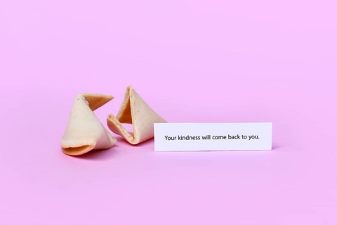 Fortune cookie with motivational text saying 'Your kindness will come back to you on pink