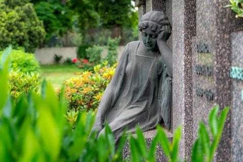 Figure in a cemetery, family grave, old gravestone, with flower and grave light, North