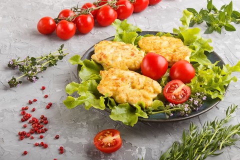 Minced chicken cutlets with lettuce, tomatoes and herbs on a gray concrete background. side view,