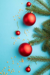 Christmas or New Year composition. Decorations, red balls, fir and spruce branches, on a blue paper
