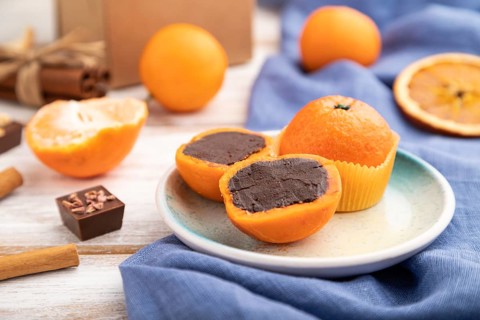 Truffle chocolate tangerine candies on a white wooden background and blue linen textile. Side view,