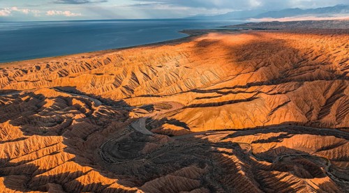 Landscape of eroded hills, badlands at sunset, Issyk Kul Lake in the background, aerial view,