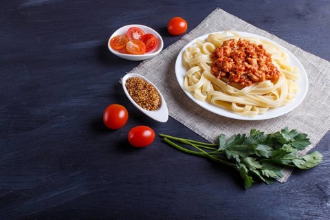 Fettuccine bolognese pasta with minced meat on black wooden background. close up, copy space