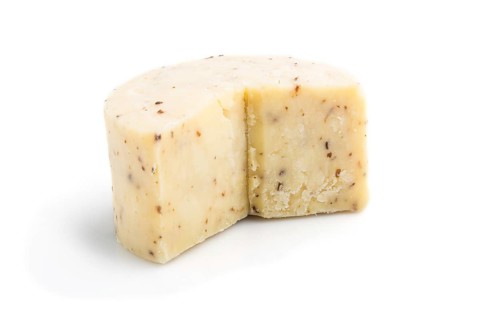 Piece of cheddar cheese isolated on white background. Side view, close up