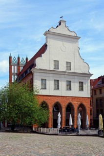 Historic gabled house on a cobbled town square with closed parasols and a tree, Old Town Hall on
