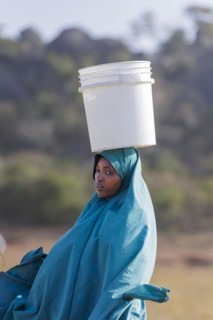 Woman with a bucket of water on her head in Maraban Dare community, Plateau state, 07/02/2024