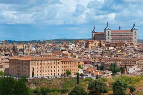 Toledo city view with historic buildings and a cathedral under a blue sky with clouds, Seminario