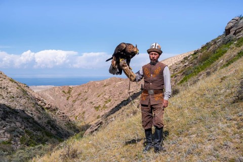 Traditional Kyrgyz eagle hunter with eagle in the mountains, near Kysyl-Suu, Kyrgyzstan, Asia