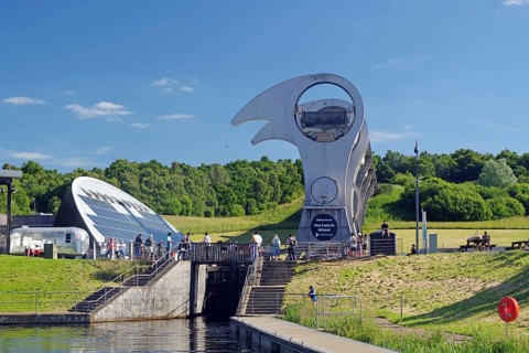 The Falkirk Wheel, a modern architectural structure, lifts boats in a hilly landscape, Forth and