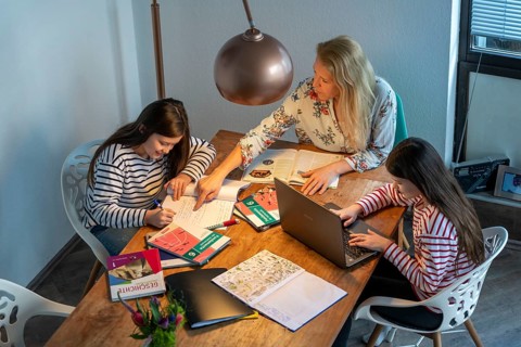 Homeschooling, during the lockdown in January 2021, mother helps her two daughters, at home,