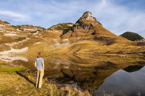 Lake Augstsee and the Atterkogel mountain on the Loser. A hiker stands on the shore. Autumn, good