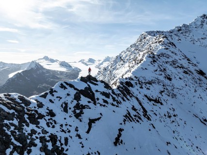 Mountaineer standing on the snow-covered Ramoljoch under a clear sky in the Alps, behind glacier
