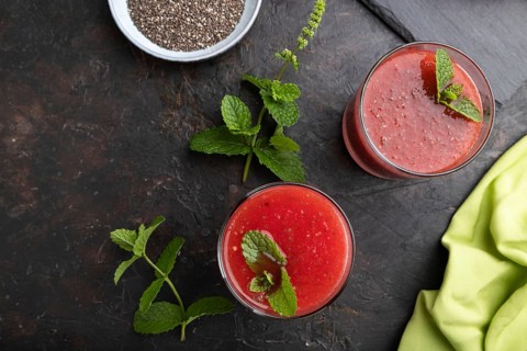 Watermelon juice with chia seeds and mint in glass on a black concrete background with green
