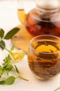 Red tea with herbs in glass teapot on white wooden background. Healthy drink concept. Top view,
