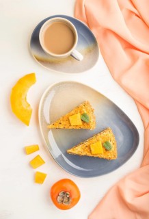 Homemade cake with persimmon and pumpkin and a cup of coffee on a white wooden background with