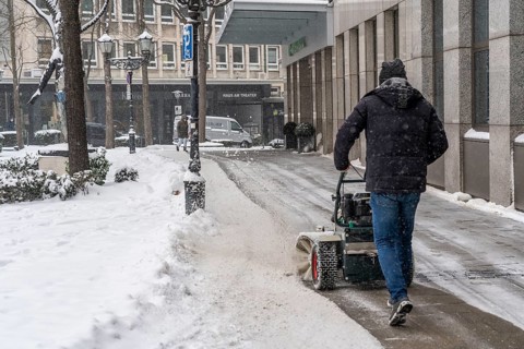 Private winter service, snow sweeper in front of a commercial building in the city centre of Essen,