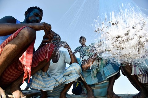 Fishermen knitting fishing net in the banks of Beki river, in Barpeta district of Assam, India on