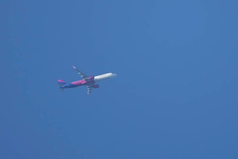 Airbus A320 aircraft of Wizz air airlines in flight across a blue sky, England, United Kingdom,