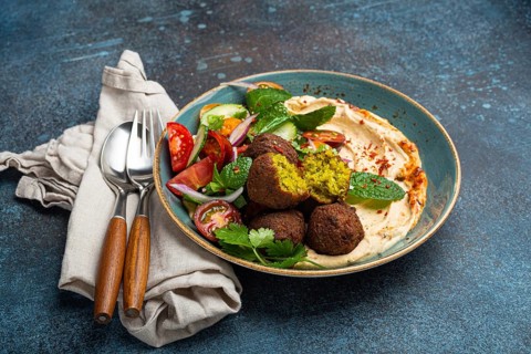 Close up of Middle Eastern Arab meal with fried falafel, hummus, vegetables salad with fresh green