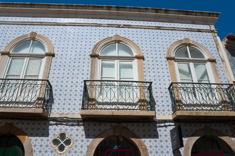 Facade of a house with blue azulejos and wrought-iron balconies in traditional Portuguese style,