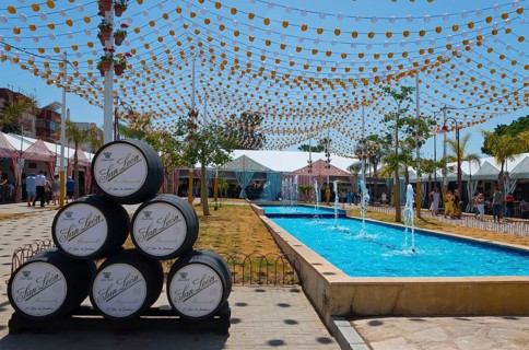 Colourful fairy lights over barrels next to a water basin, festive atmosphere, Feria de la