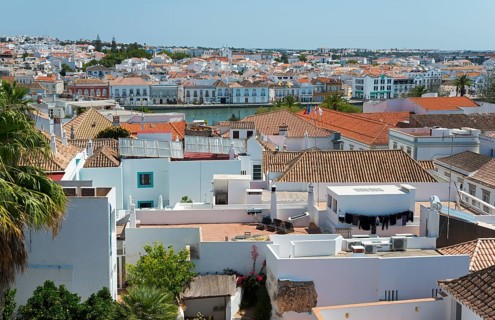 View over the roofs of a town in the Portuguese Algarve with red tiled roofs and a river in the