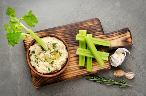 Flat lay view at vegetable Hummus dip dish topped with chickpeas and olive oil served with celery